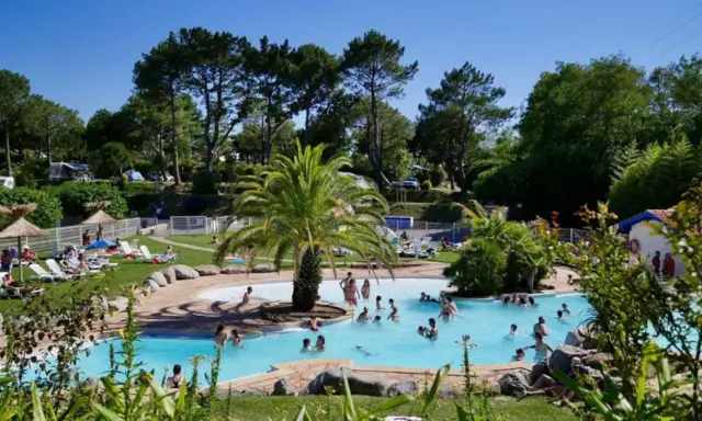 Disfruta de un día soleado en el camping de País Vasco, con una piscina refrescante y gente relajándose en tumbonas.