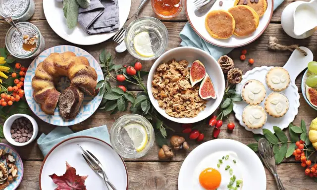 Leckere Brunch-Idee: Marmorkuchen, Müsli, Pancakes, Obst und ein Spiegelei auf rustikalem Holztisch.