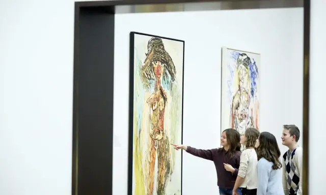 A group of children admire a painting in the style of the cobra art movement, with one girl pointing at the abstract figure.