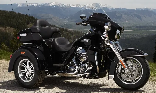 Harley-Davidson negro de tres ruedas aparcado en un paisaje montañoso. Recuerda que las motos de tres ruedas necesitan carnet de moto.