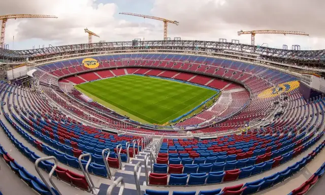 Nowy stadion Barcelony w budowie. Żurawie górują nad trybunami w barwach klubu, gotowymi na przyjęcie kibiców.