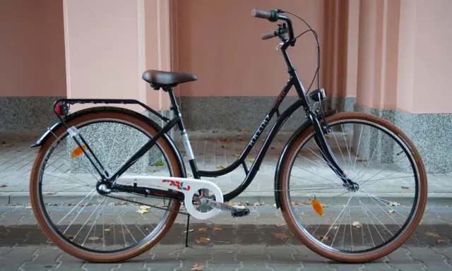 Elegancki, czarny rower do miasta z brązowymi oponami i wygodnym siodełkiem. Idealny na codzienne dojazdy.