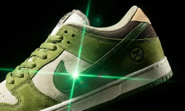 Zielone buty Nike SB Dunk z oryginalną metką, oświetlone zielonym laserem.