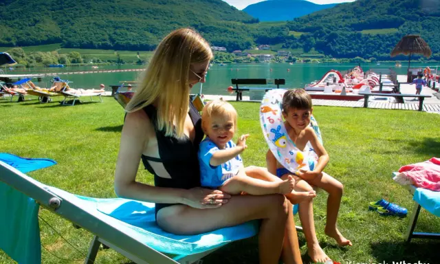 Rodzina odpoczywa nad jeziorem Lago di Caldaro. Słońce, zieleń i woda tworzą idealne wakacje.