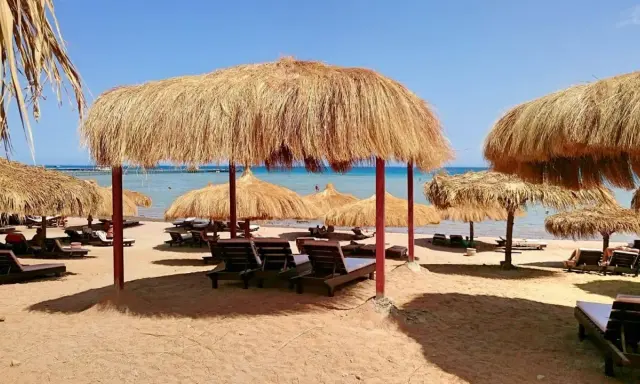 Słoneczna plaża z leżakami i parasolami z trawy. Idealne miejsce na relaks w stylu caves beach resort.