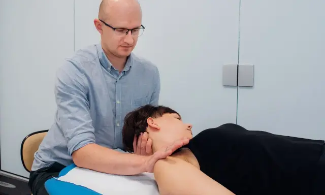 Osteopata wykonuje terapię manualną szyi pacjentki. Czy osteopata jest lekarzem? To pytanie często zadawane przez pacjentów.