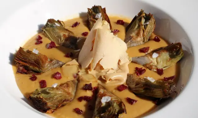 Delicioso guiso de alcachofas con trocitos de jamón y una lámina crujiente de queso.