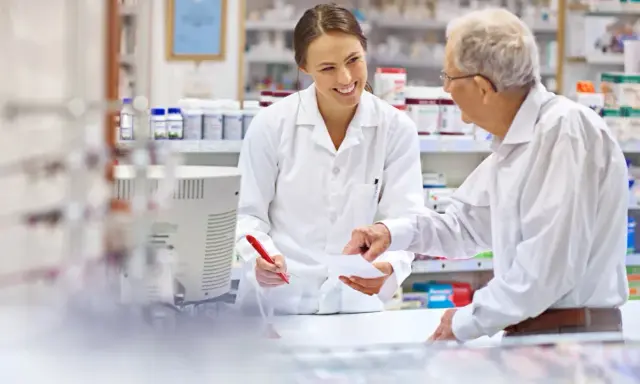 Farmaceutka wyjaśnia seniorowi, od kiedy dostępne są darmowe leki dla seniorów.