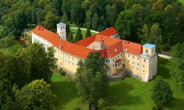Malowniczy hotel zamek otoczony zielenią.