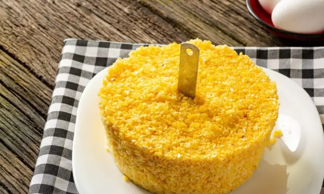Un pastel de maíz amarillo con un cuchillo insertado, listo para servir. Una guía visual para como hacer cous cous.