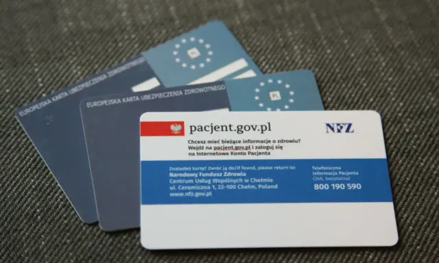Kilka kart EKUZ i karta pacjenta NFZ na szarym tle.