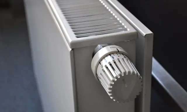 Gros plan sur un radiateur blanc, élément clé d'une installation chauffage central, avec sa molette de réglage de température.