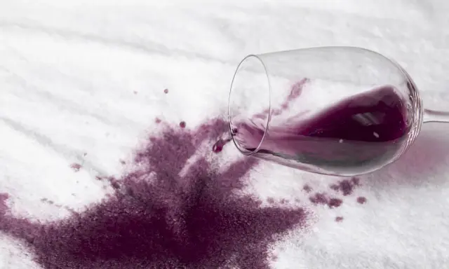 Rozlane czerwone wino na białym materiale. Jak szybko sprać czerwone wino, by ratować ulubioną tkaninę?