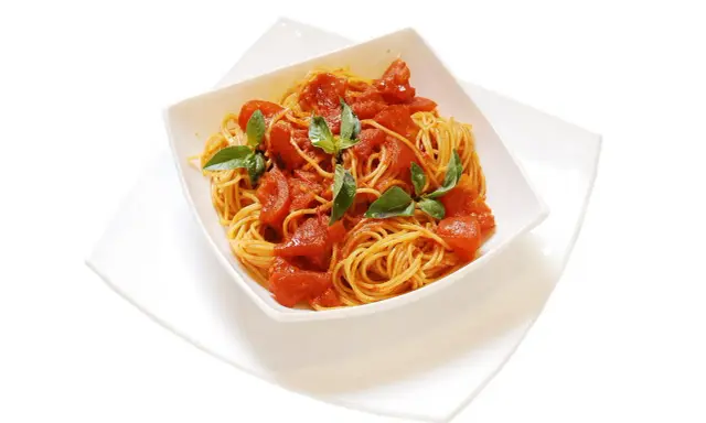 Un invitante piatto di spaghetti al pomodoro fresco, guarnito con foglie di basilico verde brillante.