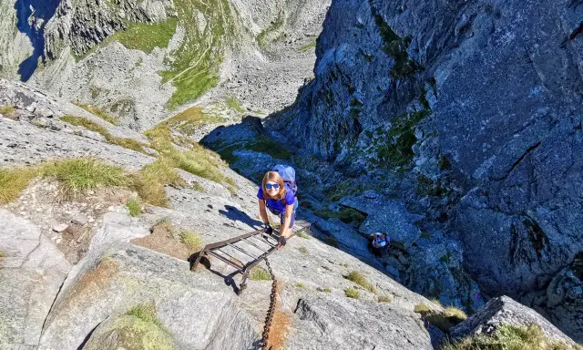 Kobieta wspina się po drabinie na Orlej Perci. Czas przejścia zależy od kondycji i pogody.
