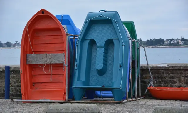 Plusieurs petites embarcations colorées, dont une annexe orange, sont rangées sur un quai.