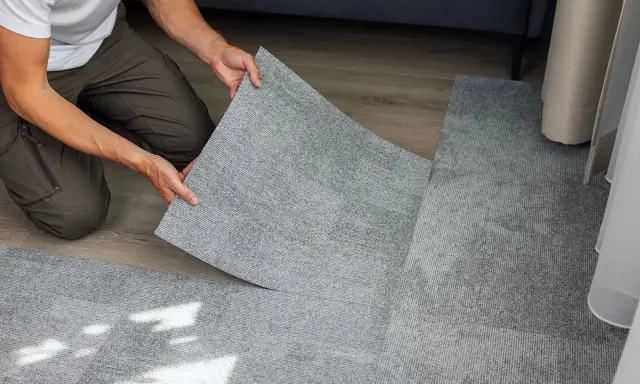 Pose d'une nouvelle moquette pour cacher un manque de carrelage. Les dalles grises s'assemblent parfaitement.