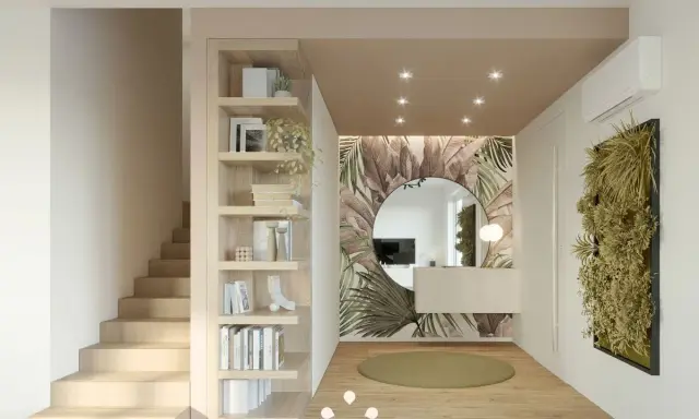 Ingresso casa elegante con libreria a giorno, scala in legno, specchio rotondo e carta da parati tropicale.