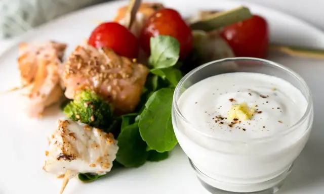 Brochettes de poisson et saumon grillés avec tomates cerises, brocolis et une sauce au yaourt crémeuse.