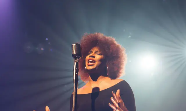 Kobieta z burzą afro włosów śpiewa do mikrofonu, jej głos jest niczym unchained melody, wolny i pełen emocji.
