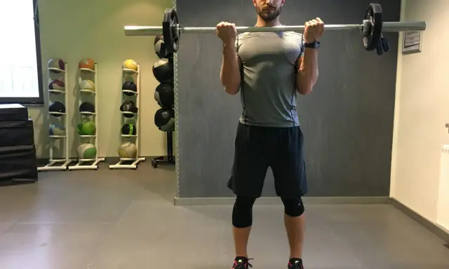 Mann macht Langhantel Curls im Fitnessstudio. Er trainiert seine Bizeps.