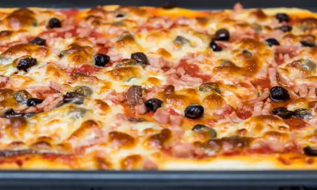 Une pizza rectangulaire garnie de jambon, d'olives et de fromage fondant. Parfait pour savoir que faire avec une pâte à pizza rectangulaire !