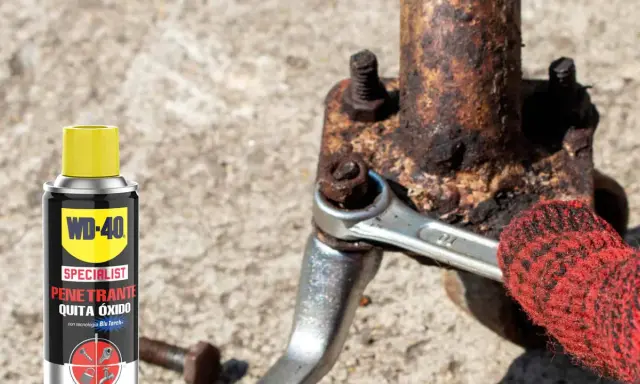 WD-40 ayuda a sacar tornillo roto de pieza oxidada. Llave inglesa y guante rojo en acción.