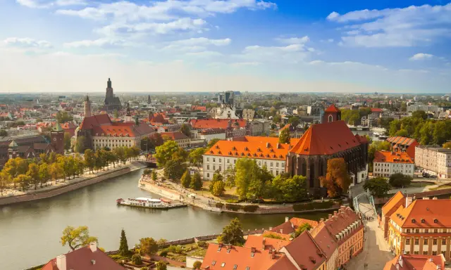 Widok na Ostrów Tumski we Wrocławiu, idealne miejsce na city break z Wrocławia. Rzeka, zabytkowe budynki i błękitne niebo.