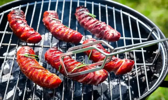 Pyszna kiełbasa z grilla, rumiana i soczysta, z gałązkami rozmarynu, pieczona na węglu.