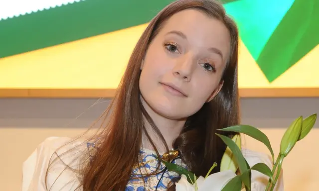 Sanah z bukietem białych lilii, uśmiechnięta, jakby przeżywała najlepszy dzień w moim życiu.