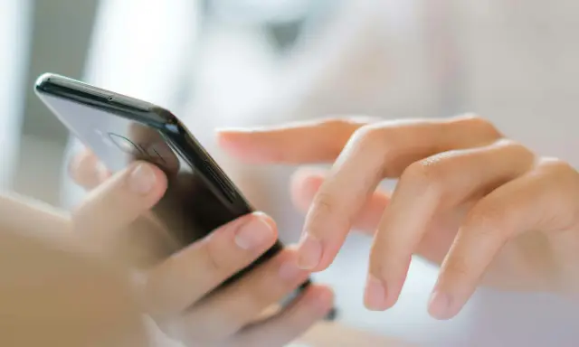 Dłonie wpisują numer referencyjny przesyłki na ekranie smartfona.