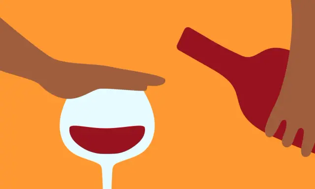 En hand stoppar ett glas rött vin medan en flaska hälls. Kanske en påminnelse om att vara försiktig med alkohol, särskilt om man tar medicin som Diamox.