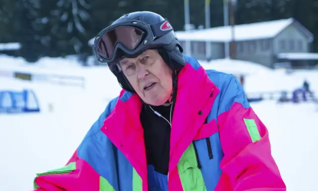 Äldre man i färgglad skidjacka och hjälm, redo för backen. Kanske en veteran från Edsbyn skidor.