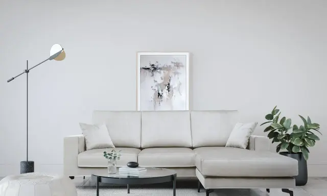 Divano angolare color crema, con tavolino rotondo in vetro e pouf bianco. Le misure del divano angolare sono perfette per questo spazio.