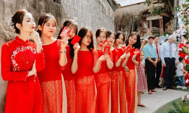 Novias y damas de honor con trajes rojos tradicionales, sosteniendo sobres rojos, celebrando una boda china.