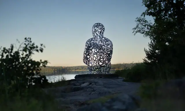 Skulptur av bokstäver vid Artipelag Stockholm, med en sjö i bakgrunden.