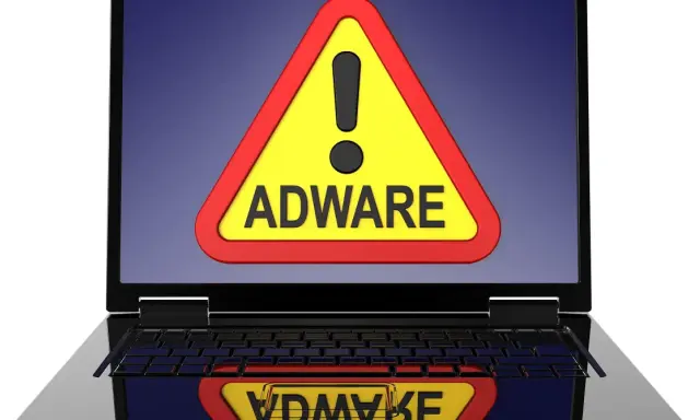 Warnung auf Laptop-Bildschirm: gelbes Dreieck mit Ausrufezeichen und dem Wort "ADWARE". Ein Adware-Virus ist eine Bedrohung.