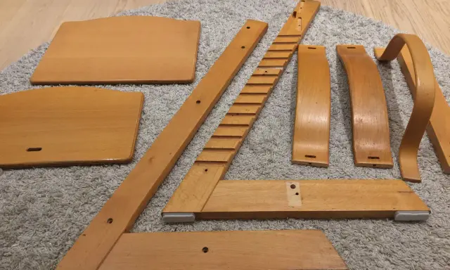 Delar av en Stokke stol ligger utspridda på en matta, redo att måla om.