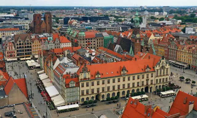Widok z góry na kolorowy rynek z kamienicami, ratuszem i kościołem. To chyba najładniejszy rynek w Polsce, tętniący życiem.