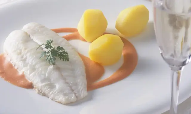 Ein zartes Steinbuttfilet mit Petersilie, serviert mit Salzkartoffeln und einer cremigen Sauce. Der feine Steinbutt Geschmack verspricht ein kulinarisches Erlebnis.