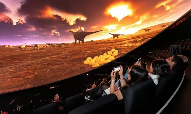 Besökare njuter av en dinosaurieupplevelse i en kupolformad salong, som en del av universum i Göteborg.