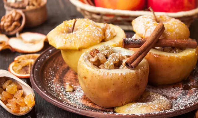 Manzanas asadas rellenas de pasas y canela, espolvoreadas con azúcar glas. Un postre casero y reconfortante.