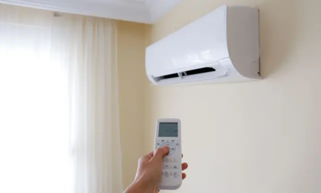 Mano che regola il climatizzatore per un ambiente fresco e dry.