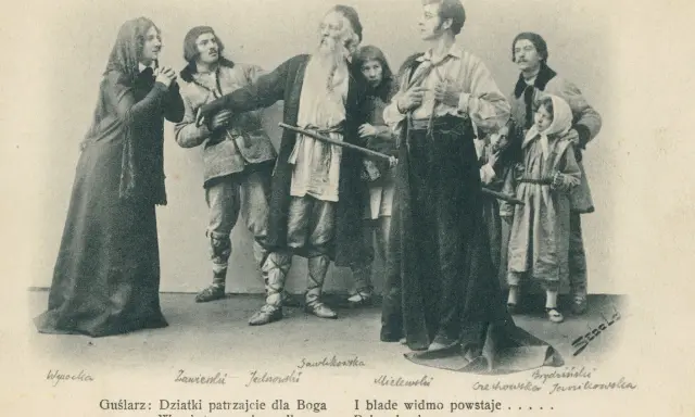 Grupa postaci w strojach ludowych, w tym starszy mężczyzna z brodą, młodzi ludzie i dzieci.