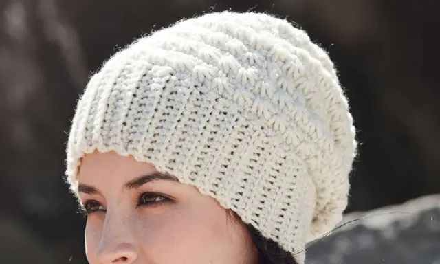 Mujer con gorro de ganchillo blanco con patrón texturizado. ¡Encuentra gorros de ganchillo patrones gratis para crear el tuyo!
