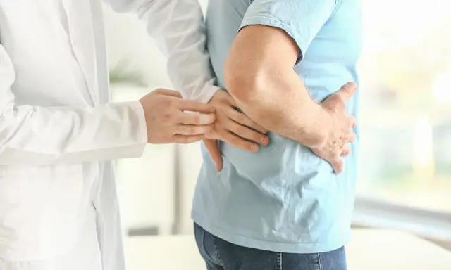 Lekarz bada pacjenta z bólem w boku, sugerującym rozbijanie kamieni nerkowych.