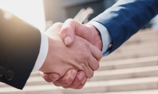 Umorzenie postępowania egzekucyjnego zakończone uściskiem dłoni. Dwie osoby w garniturach potwierdzają porozumienie.