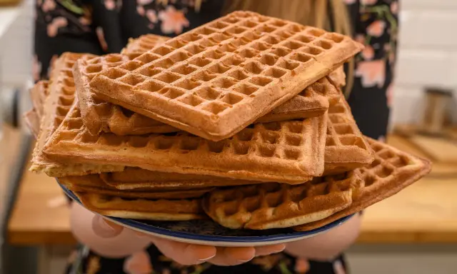 Une assiette débordante de gaufres dorées, parfaites pour une recette de gaufres croustillantes et moelleuses. Un délice à partager !