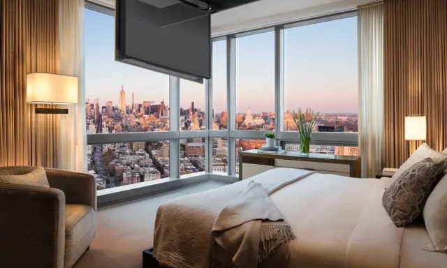 Camera da letto con vista su New York, dove una tv nascosta a soffitto scompare quando non serve, lasciando spazio al panorama.