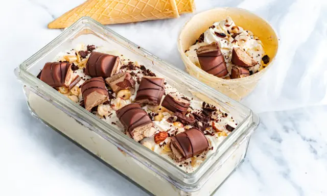 Lody Kinder Bueno w pojemniku i wafelku, posypane orzechami i czekoladą.